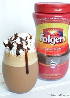 a cup of coffee next to a container of foger's chocolate frosting