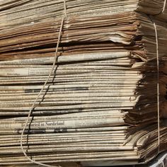 an old stack of newspapers sitting on top of each other next to a pile of string