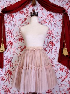 This historically inspired skirt is the very vision of Edgar Degas' paintings and sculptures based on the ballet dancers of 19th-century Paris. With frilly tiered layers of mesh, a delicate nude-pink hue, dainty ribbons throughout, and a finishing rosette embellishment, you're sure to be The Star on the stage! Sizing: ✧IN✧ Waist Hips Length S/M 24-38 Inches Up to 50 Inches 18.5 Inches L/XL 28-42 Inches Up to 58 Inches 19.5 Inches ✧CM✧ Waist Hips Length S/M 60-96 CM Up to 127 CM 47 CM L/XL 71-106 CM Up to 147 CM 49.5 CM Materials:100% Polyester Mesh Care:Gently handwash or dry clean only. Do not tumble dry. Pink Tiered Petticoat With Attached Cancan, Pink Ruffled Tiered Petticoat, Pink Flowy Tiered Skirt Petticoat, Pink Flowy Tiered Petticoat, Pink Ruffled Balletcore Skirt, Pink Ruffled Skirt In Balletcore Style, Pink Tiered Skirt With Attached Cancan, Pink Balletcore Skirt With Ruffles, Fitted Pink Balletcore Skirt