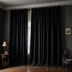 a living room with black curtains and wooden floors