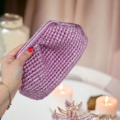 a woman's hand holding a purple purse over a table with candles on it