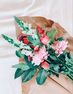 a bouquet of flowers sitting on top of a piece of brown paper with green leaves