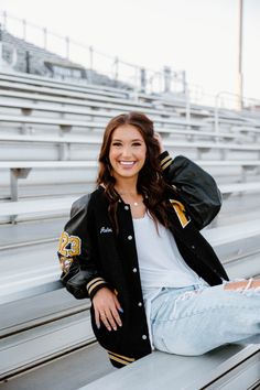 a woman is sitting on the bleachers and smiling at the camera with her arms behind her back