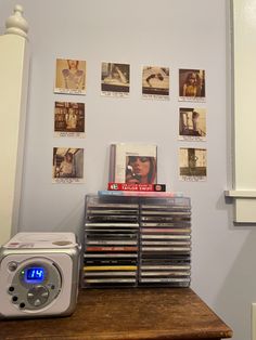 a radio sitting on top of a wooden table next to a wall covered in pictures