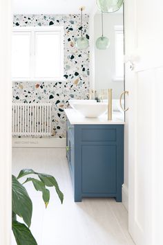 a bathroom with a sink, mirror and green plant in it's corner next to the radiator