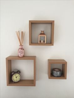 three wooden cube shelves with candles and other decorative items on them, against a white wall