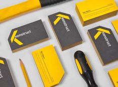 some business cards and tools are laid out on a white surface with yellow lettering that says construction