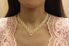 a close up of a woman wearing a pink dress and gold necklace on her neck