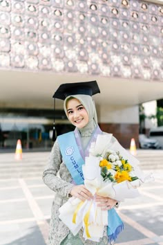 a woman in a graduation gown holding flowers