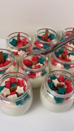 small glass jars filled with white and red desserts next to a pair of scissors