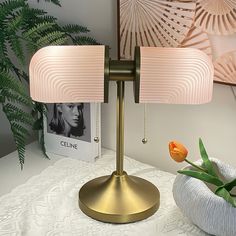 a table lamp sitting on top of a white table next to a potted plant