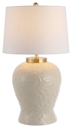 a white vase with a gold base and a light shade on the top is sitting in front of a white background