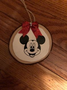 a wooden ornament with a minnie mouse face on it and a red bow