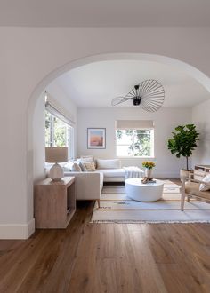 a living room with white furniture and wood floors