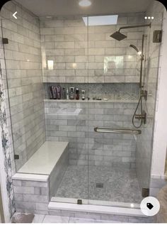 a walk in shower sitting next to a white tiled wall and floor with glass doors