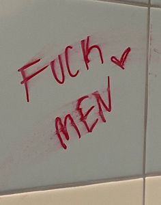 graffiti written on the side of a bathroom wall