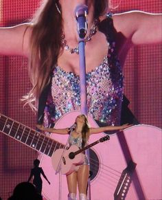 the woman is singing on stage with her guitar