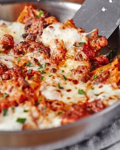 a close up of a pizza in a pan on a table with a spatula