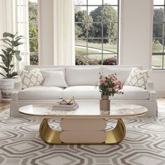 a living room with white couches and a coffee table in front of two windows