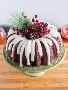 a chocolate bundt cake with icing and pine cones on top, sitting on a green plate