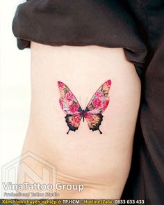 a butterfly tattoo on the side of a woman's thigh, with pink flowers