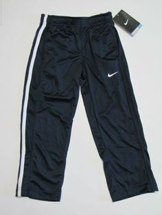 a pair of black nike pants with white stripes and a book on the floor next to it