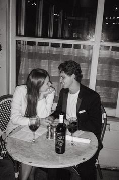 two people sitting at a table with wine glasses