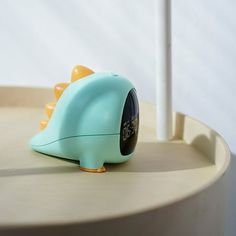 a blue alarm clock sitting on top of a table next to a toothbrush holder