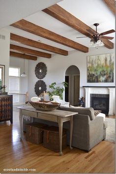 a living room filled with furniture and a fire place next to a fireplace covered in wood beams