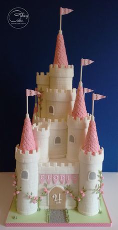 a birthday cake made to look like a castle with pink turrets and flags on top