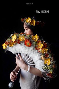 a woman is holding a fan with flowers on it