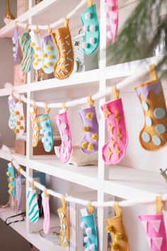 there are many christmas stockings hanging on the wall in this room and one is decorated with gold, pink, blue, and green stocking