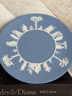 a white and blue plate with an image of people on it's center circle