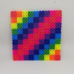 a multicolored square made out of perforated beads on a white surface