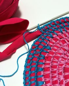 crocheted red and blue doily with yarn next to it on a white surface