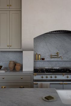 a kitchen with marble counter tops and gold accents on the hood, cabinets, and stove