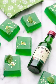 a bottle of jameson sitting on top of green pieces of wax next to small white flowers