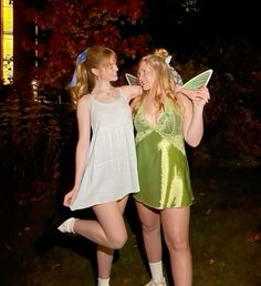 two young women dressed in green and white posing for the camera with one holding a butterfly