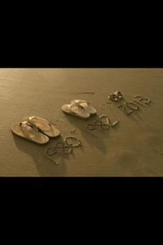 three pairs of sandals are laying on the sand