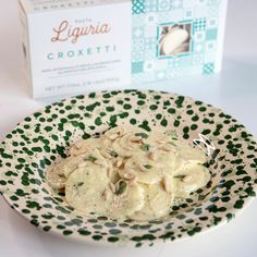 a white plate topped with ravioli next to a box of ligura croxeti