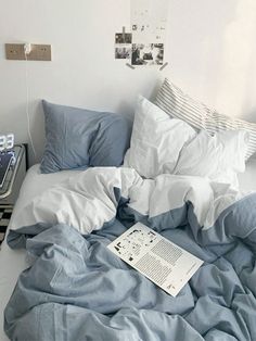 an unmade bed with blue sheets and pillows