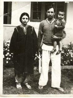 an old black and white photo shows a man holding a baby while standing next to two women