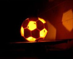 a glowing soccer ball sitting on top of a shelf next to a wall with light coming from it