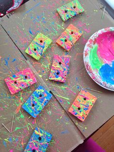 the table is covered in colorful paint and paper plates with sticks sticking out of them