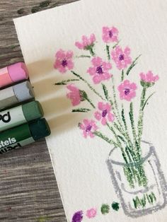 three crayons are next to some pink flowers in a vase on a piece of paper