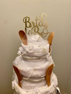 a white wedding cake with wooden utensils on top