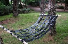 a blue hammock hanging in the middle of a park with trees around it