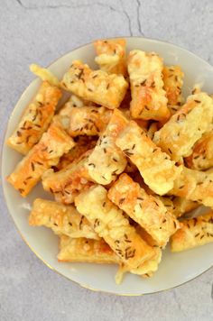 a white plate topped with cheesy crackers on top of a cement floor