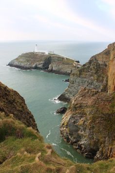 a lighthouse on top of a cliff overlooking the ocean and cliffs with grass growing around it