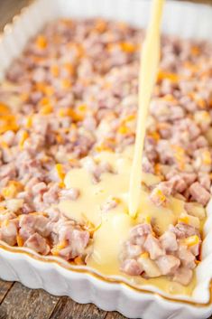 a casserole dish filled with meat and cheese being drizzled over